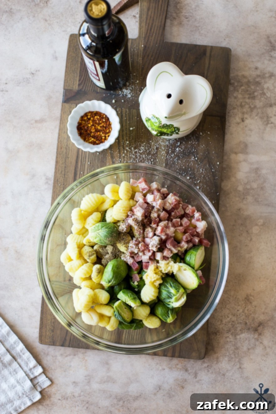 One-Pan Gnocchi Feast with Pancetta and Roasted Brussels 4 Overhead photo of a glass bowl filled with pre-baked gnocchi, pancetta, and Brussels sprouts, ready for the oven