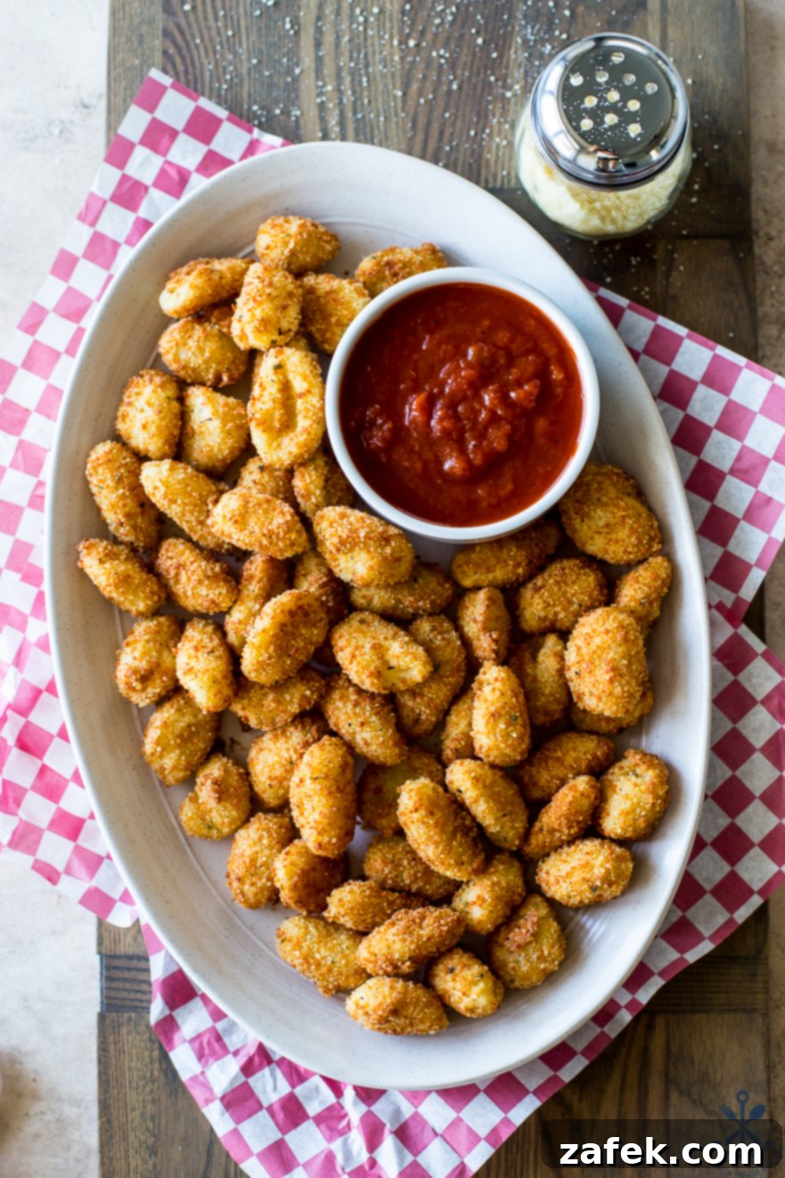 Crispy Gnocchi Delights 5 Up close overhead photo of perfectly toasted gnocchi bites, featuring their crispy texture, with a small bowl of marinara sauce and a sprig of fresh basil