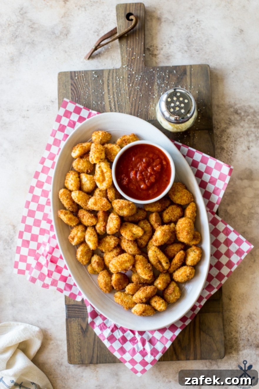Crispy Gnocchi Delights 7 Toasted Gnocchi Bites arranged on an elegant oval plate with a side bowl of marinara sauce, set on a cheerful red and white checkered paper liner, ready for a festive gathering.