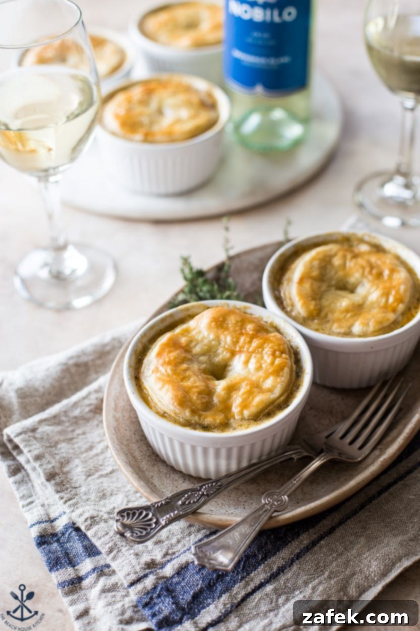 Flaky Puff Chicken Pot Pie 2 A perfectly golden Puff Pastry Topped Chicken Pot Pie served on an oval plate, with a glass of red wine in the soft-focus background, evoking a cozy fall evening.