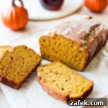 Cozy Maple Kissed Pumpkin Bread 10 A loaf of pumpkin bread with a maple glaze with two slices