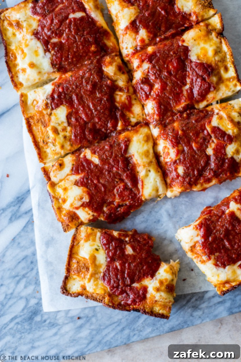 Up close overhead photo of slices of Detroit-Style pizza on a marble board