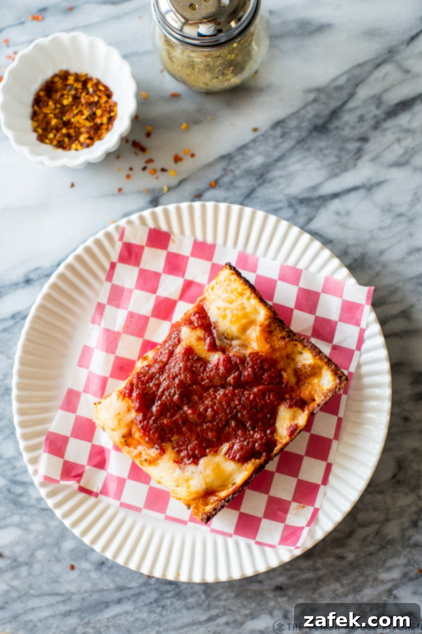 Up close overhead photo of a slice of Detroit-Style pizza on a plate