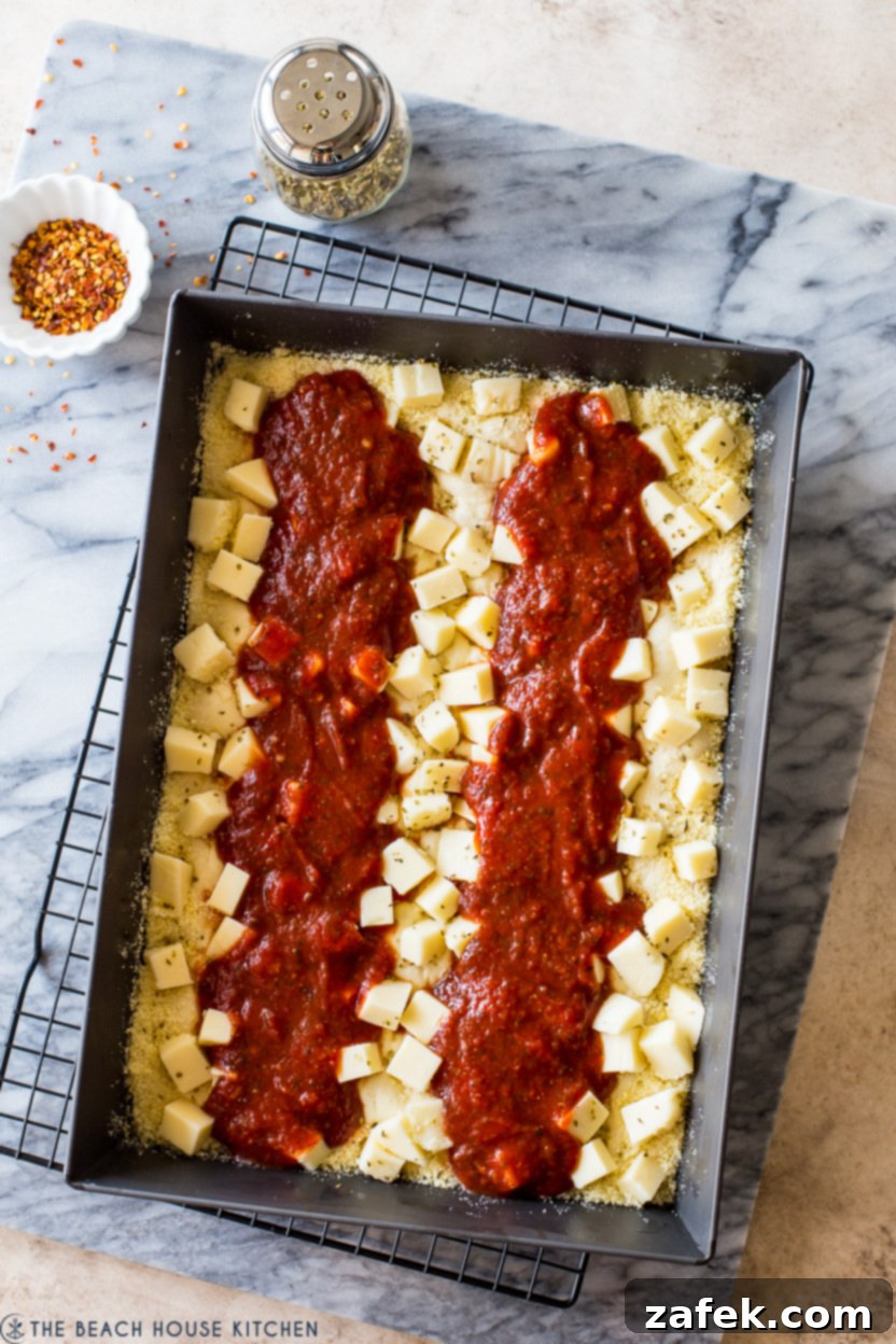 Overhead photo of a pre-baked Detroit-Style pizza with sauce stripes