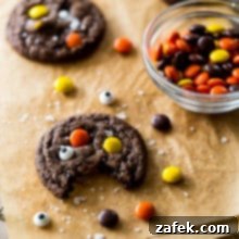 A perfectly baked chocolate Reese's Pieces cookie with googly eyes, featured in a recipe card