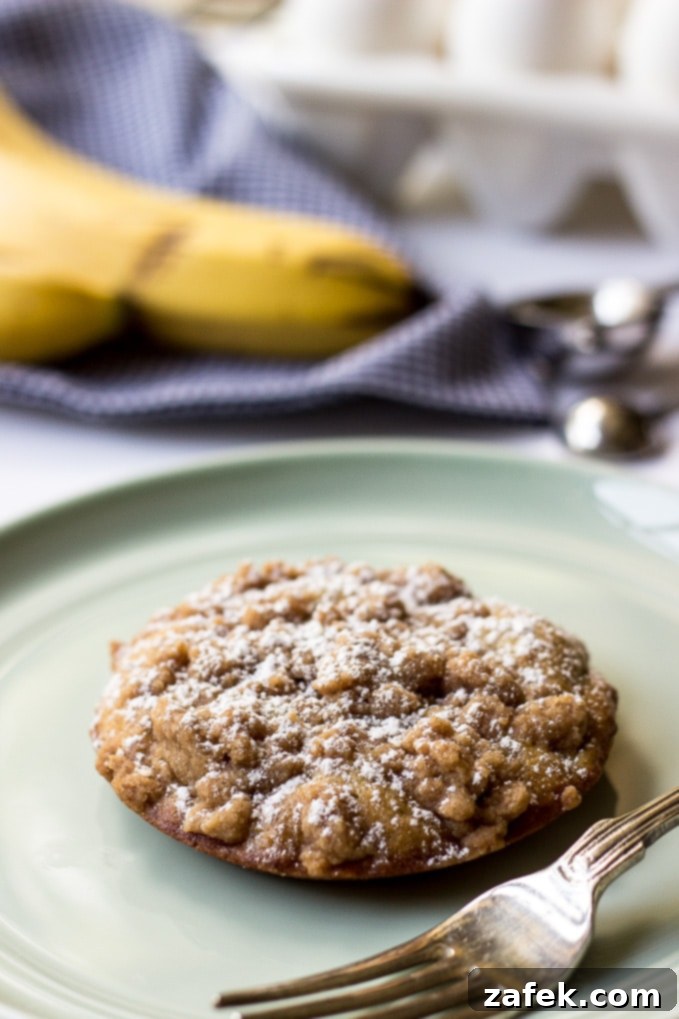 Banana Crumb Cake Muffin Tops - A single muffin top with a bite taken out, showing the moist interior.
