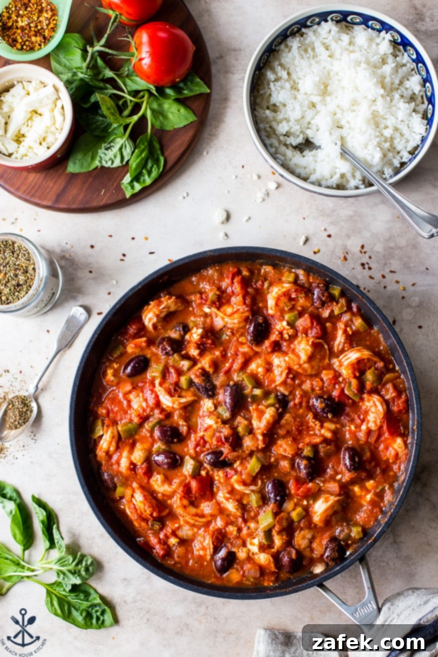 Greek-Style Baked Shrimp with Feta and Olives 5 Overhead photo of a piping hot skillet filled with the baked shrimp dish, rich in tomato sauce, feta, and Kalamata olives, served alongside a bowl of fluffy white rice
