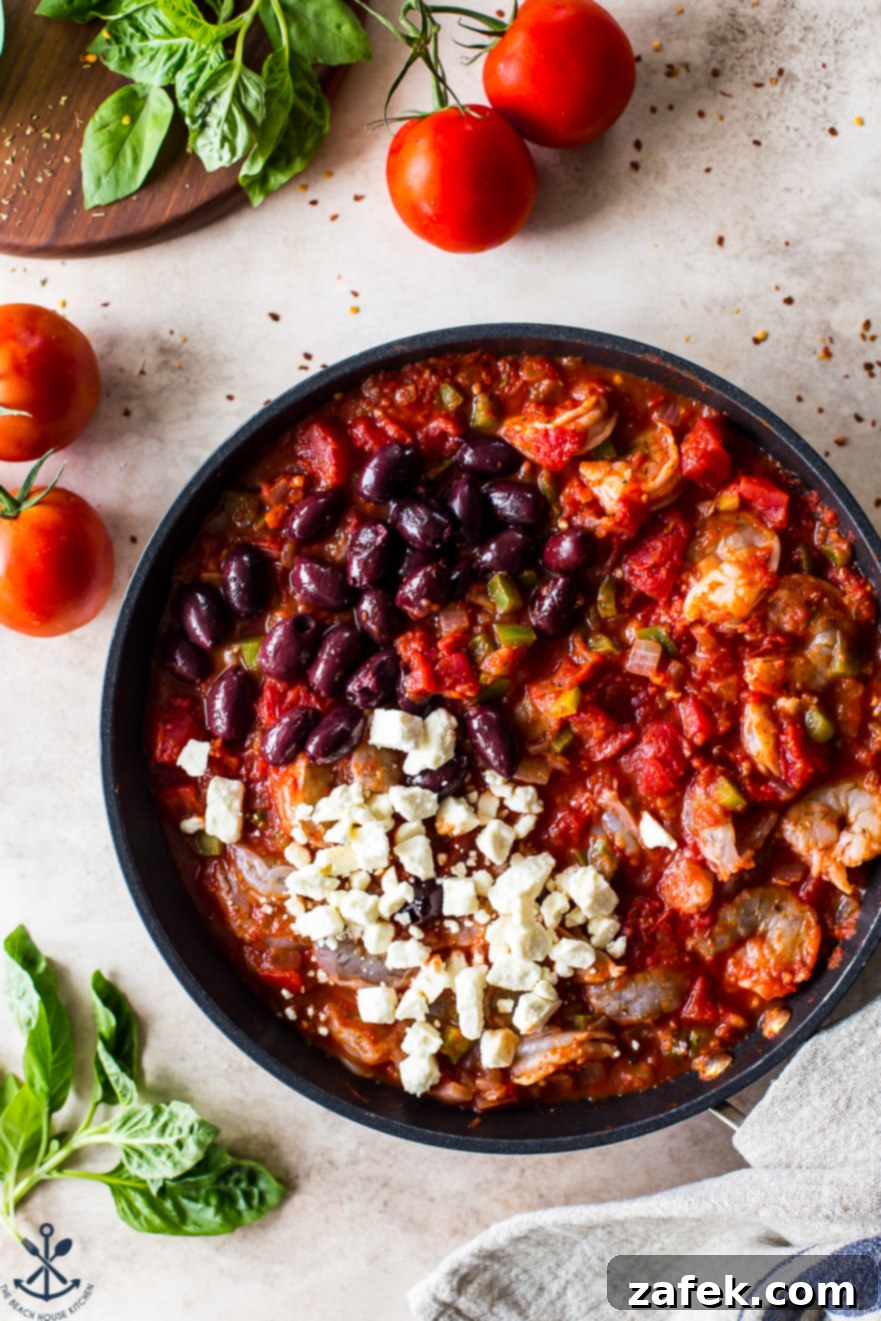 Greek-Style Baked Shrimp with Feta and Olives 8 Up close overhead photo of a skillet filled with the finished baked shrimp dish, generously topped with Kalamata olives and crumbled feta cheese