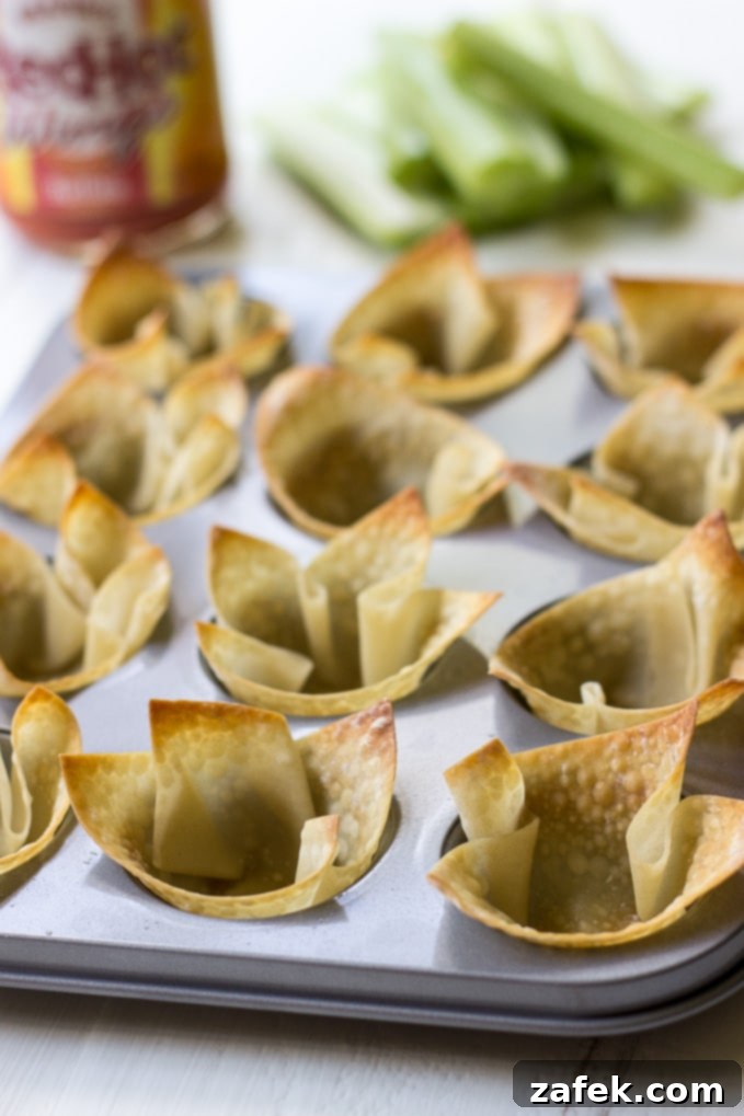 Hands reaching for a Buffalo Chicken Wonton Cup, highlighting its grab-and-go appeal.
