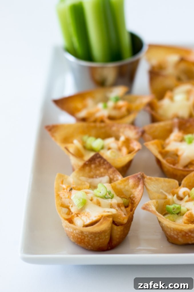 A tray of Buffalo Chicken Wonton Cups with a bowl of ranch dressing and celery.