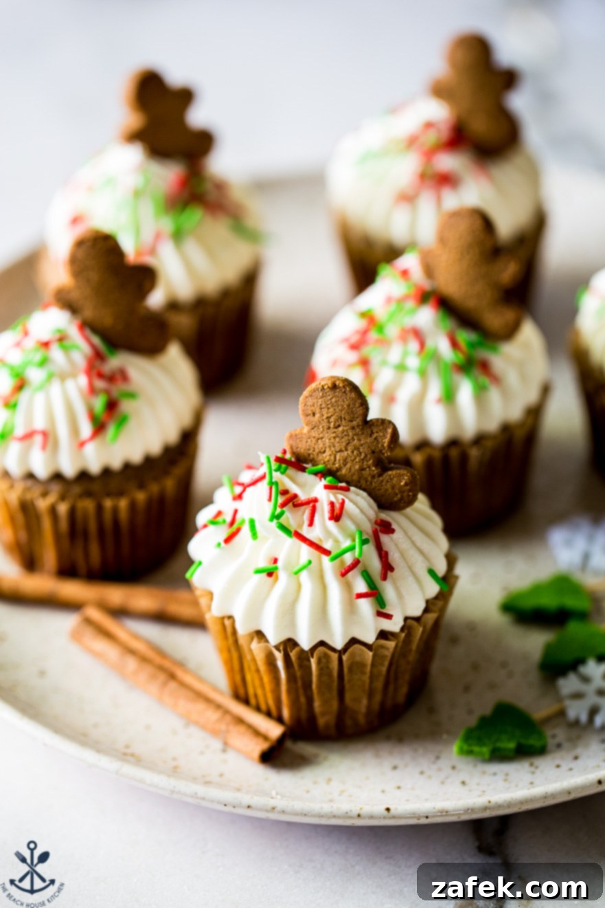 Up close photo of a cream cheese frosted chai cupcake topped with a gingerbread man mini cookie