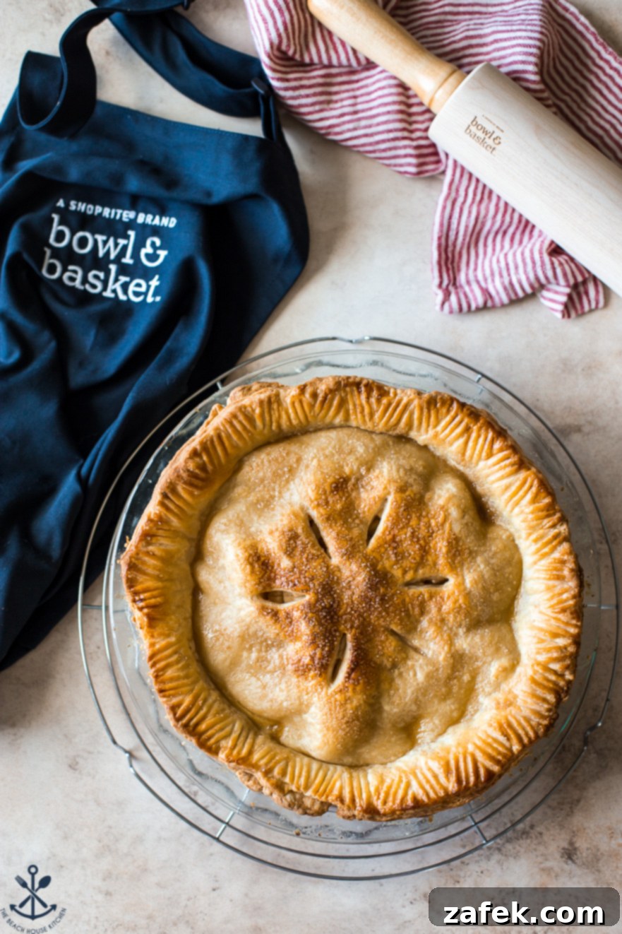 ShopRite's Holiday Apple Pie Fest 2 Overhead photo of a golden-brown apple pie with a blue apron off to the side, symbolizing the ShopRite Apple Pie Baking Event.