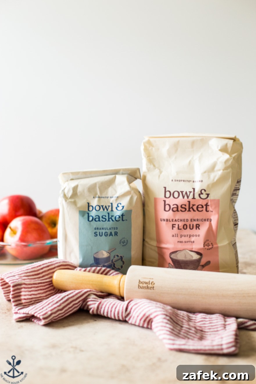 ShopRite's Holiday Apple Pie Fest 5 A wooden rolling pin rests beside bags of ShopRite Bowl & Basket flour and sugar, with fresh Gala apples in the background, ready for baking.