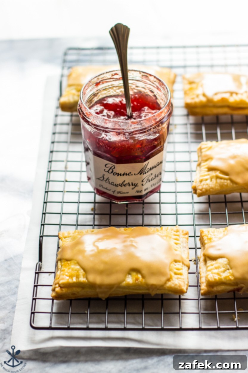 A jar of jelly with some homemade peanut butter and jelly pop-tarts on a wire rack