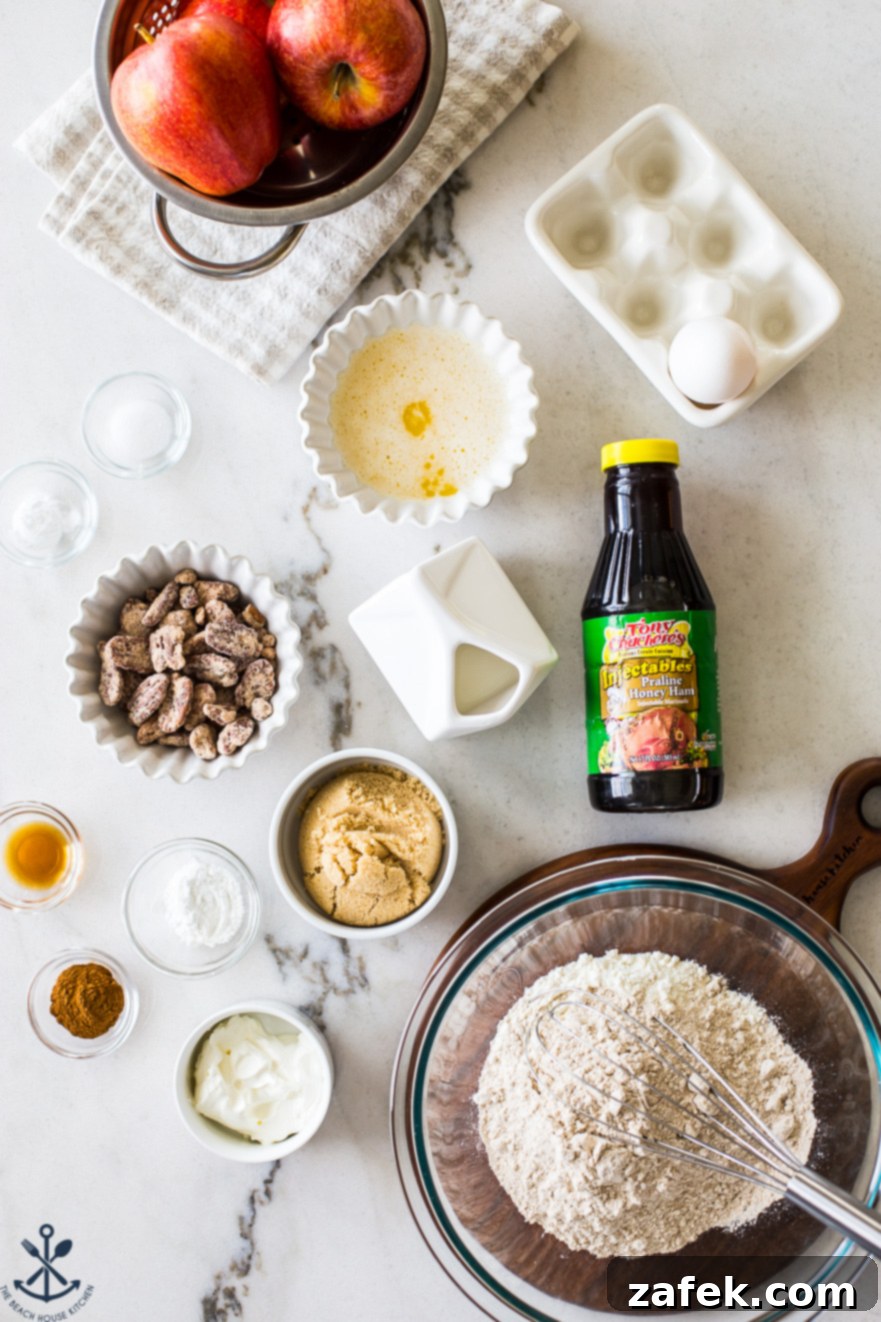 Golden Apple Praline Muffins 7 An organized overhead photo showcases a variety of muffin ingredients neatly arranged in individual bowls on a wooden surface. Flour, sugars, cinnamon, and freshly shredded apples are prominently displayed, highlighting the careful preparation process before baking.