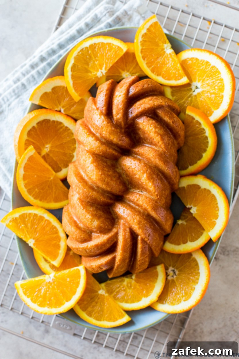 Up close overhead photo of an orange loaf cake on a plate surrounded by orange slices