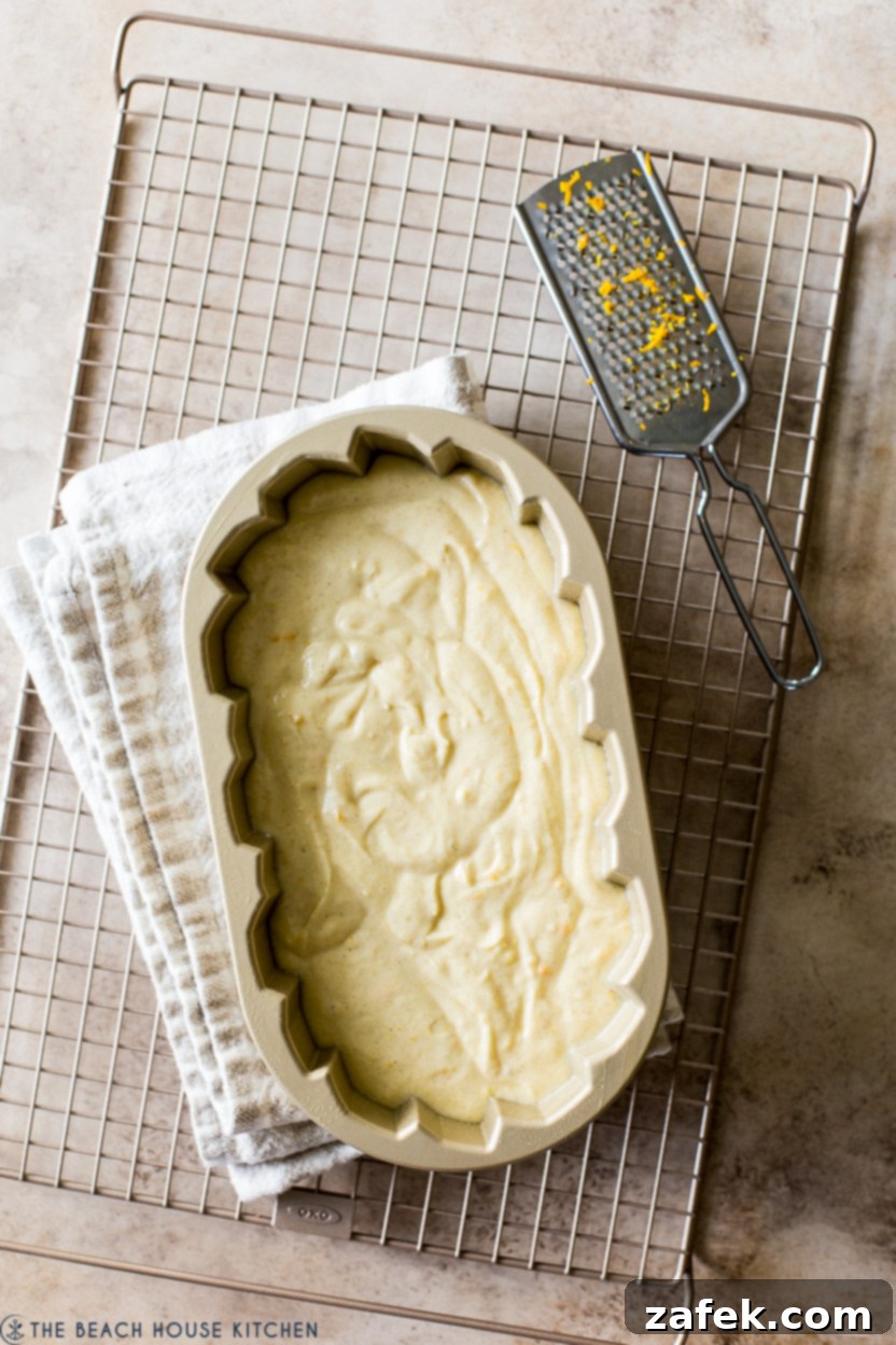 Overhead photo of a pre-baked loaf cake in a loaf pan on a wire rack