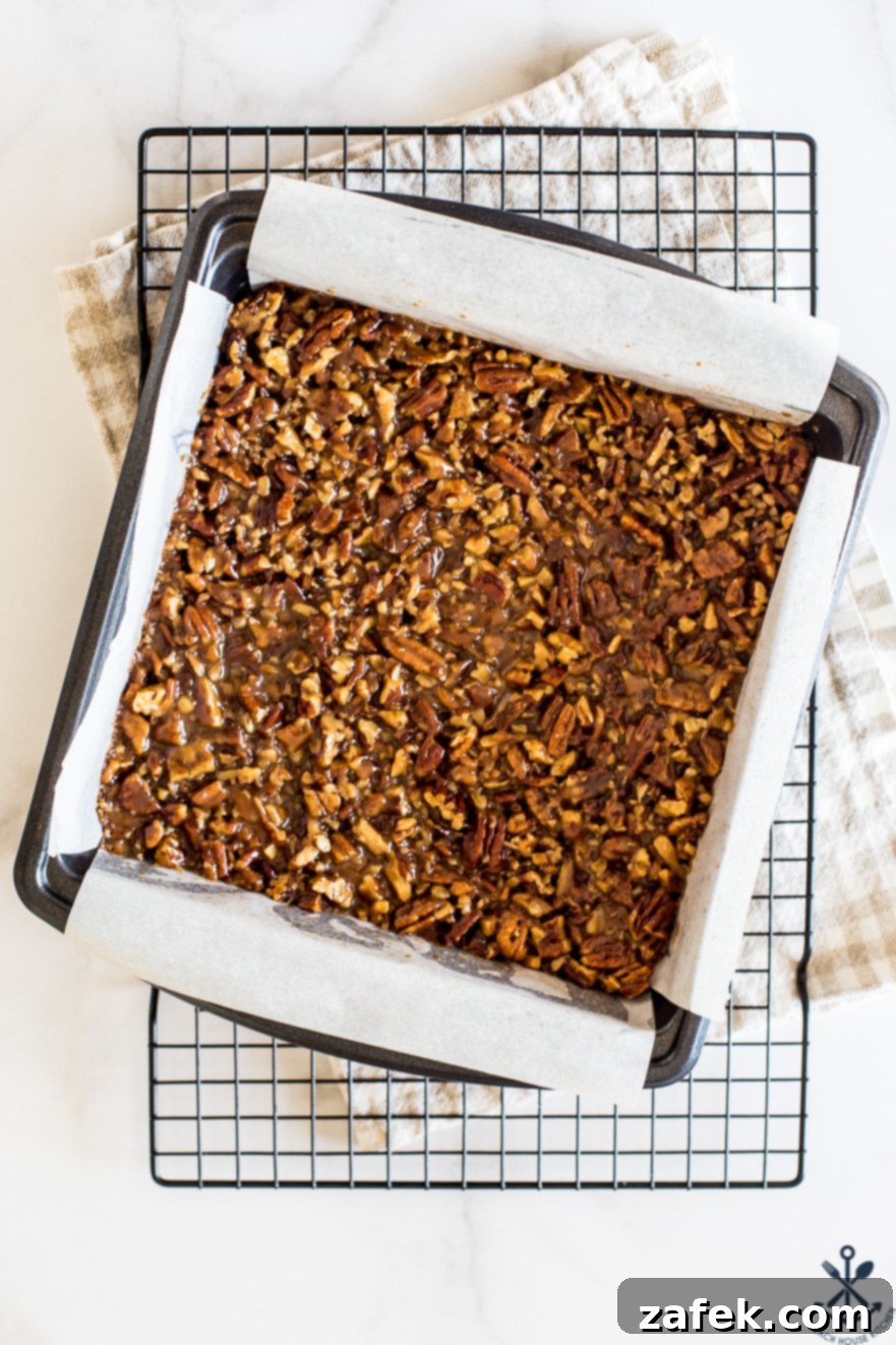 Decadent Maple Pecan Bars Adorned with Chocolate 4 Overhead photo of a full 9x9 pan of baked maple pecan bars before cutting, revealing the golden-brown, bubbly topping