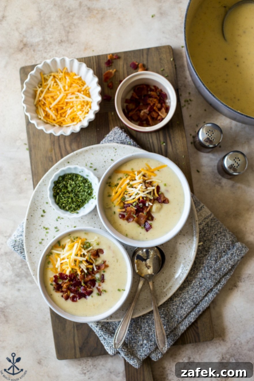 Bacon Cheddar Baked Potato Soup 6 Overhead photo of two bowls of soup on a plate with spoons and a small bowl of chopped chives