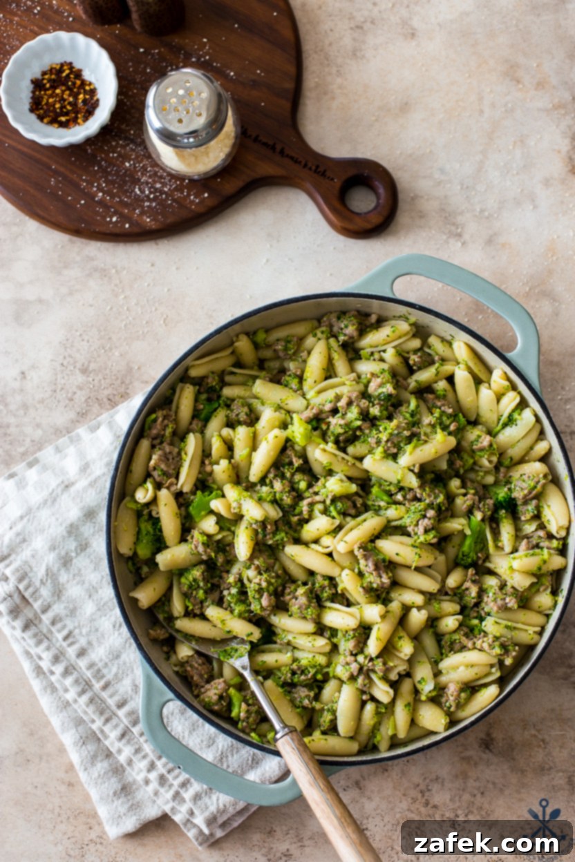 Overhead photo of a round baking skillet with pasta, broccoli and sausage
