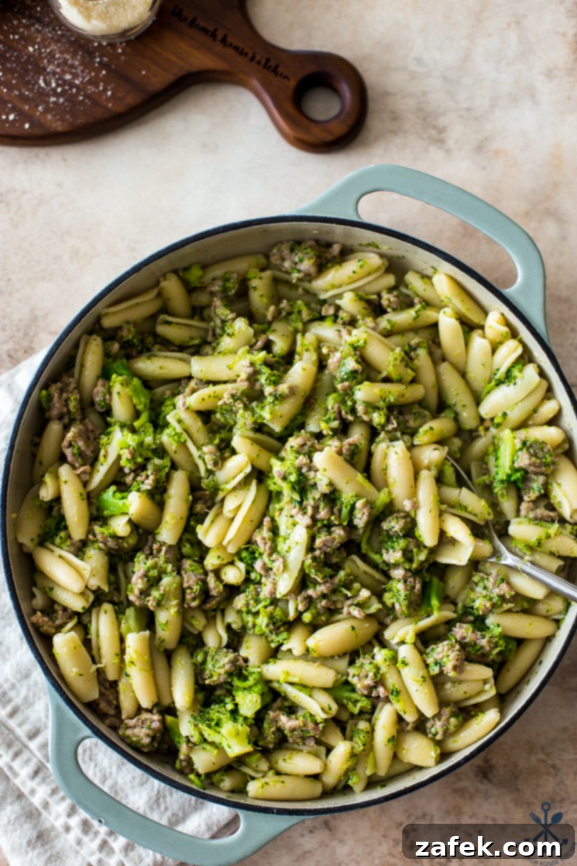 Up close overhead photo of a large skillet of pasta with broccoli and Italian sausage