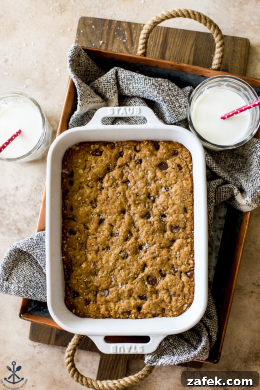 Chewy Oatmeal Chocolate Chip Bars 6 Overhead photo of baked chocolate chip oatmeal bars in a tray with two glasses of milk beside them