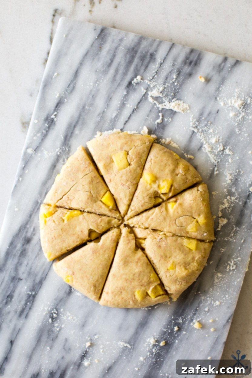 Overhead photo of pre-baked lime glazed mango toasted coconut scones arranged on a marble board, ready for glazing.