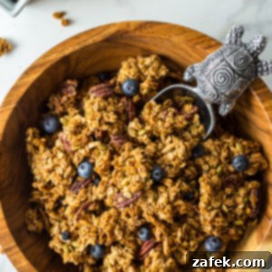 Sunshine Lemon Berry Crunch 9 Up close overhead photo of a wooden bowl of blueberry lemon granola with a silver turtle scooper