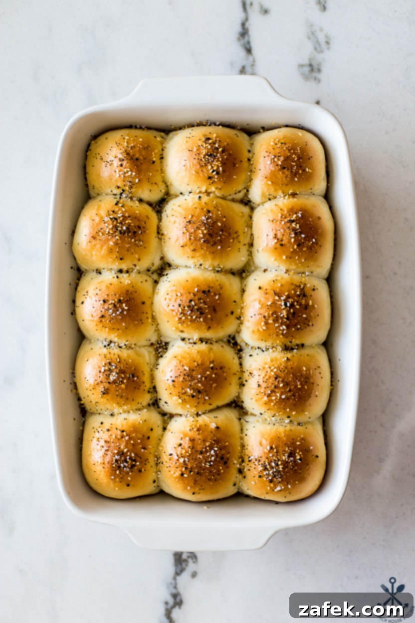 Overhead photo of a baking dish of Soft Everything Dinner Rolls, perfectly golden brown and topped with seasoning