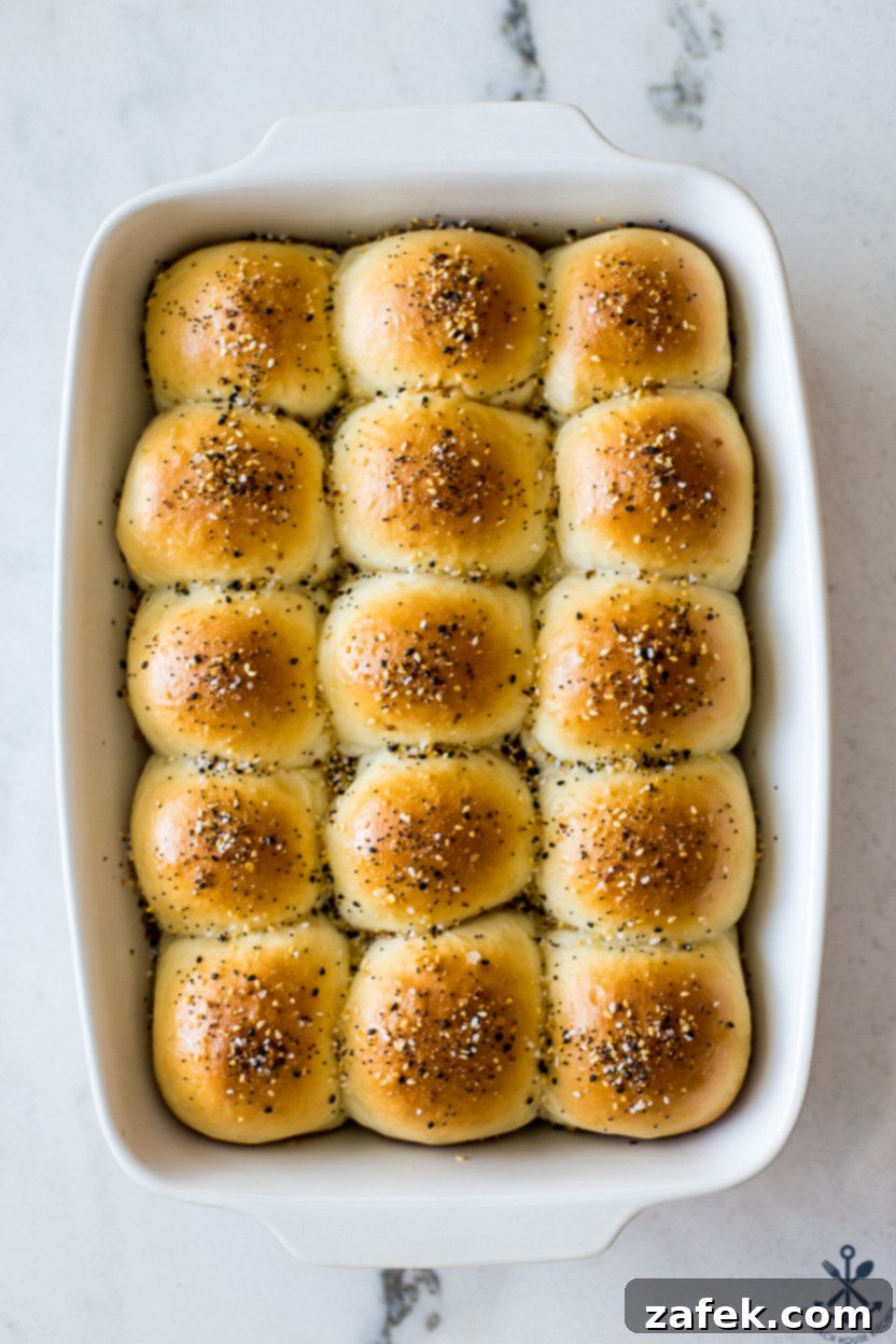 Up close overhead photo of a baking dish of everything dinner rolls, showing the golden crust and sesame seeds