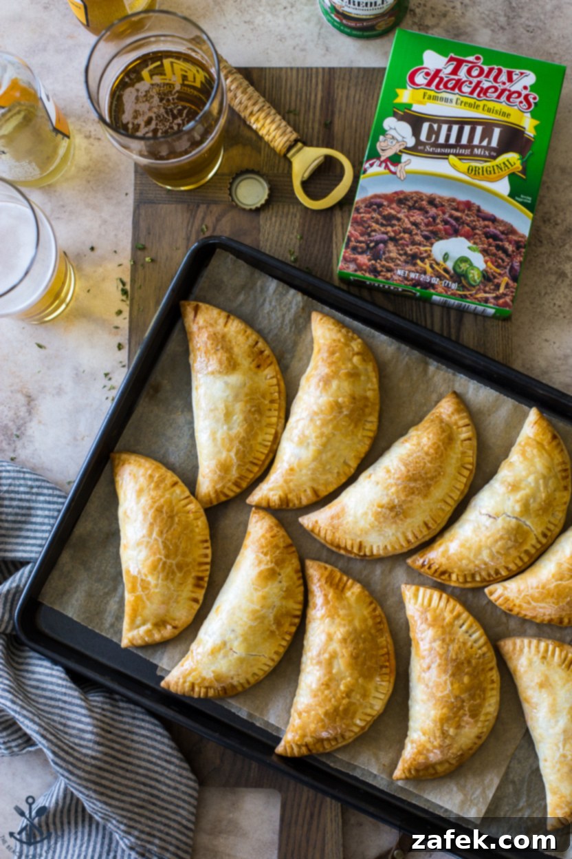 Spicy Cheesy Empanadas 7 A plate of golden brown Baked Chili Cheese Empanadas, with one cut open to show the filling.