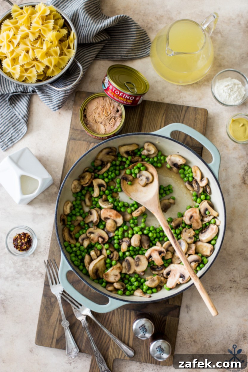 Savory Tuna Pasta with Earthy Mushrooms and Sweet Peas 4 Overhead photo of a skillet of peas and mushrooms on a wooden board