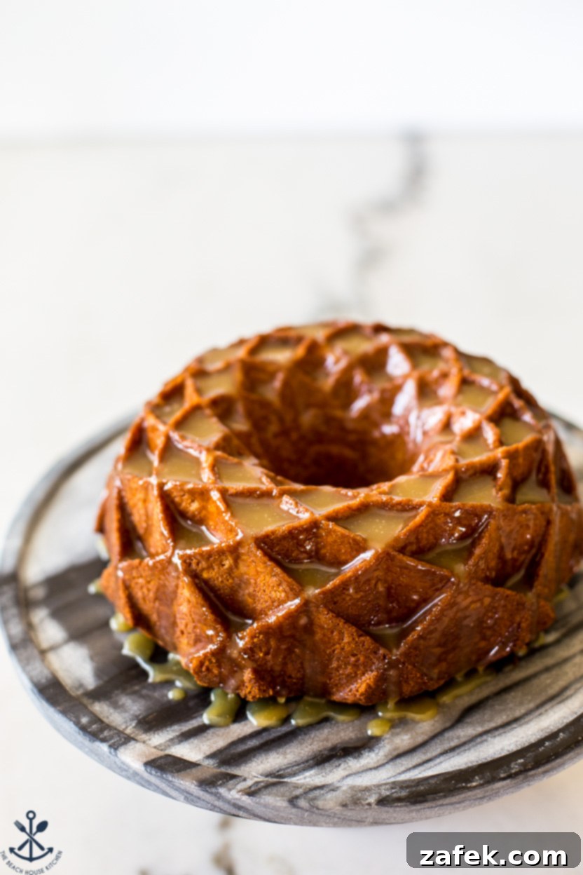 A beautifully glazed brown sugar bundt cake on a round marble cake stand, showcasing its intricate design and glistening caramel topping.