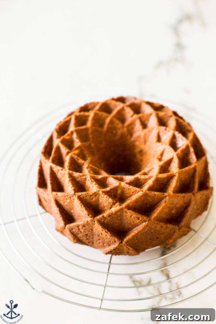 Up close photo of a freshly baked, unglazed brown sugar bundt cake cooling on a wire rack, its intricate pattern visible and ready for the decadent caramel topping.