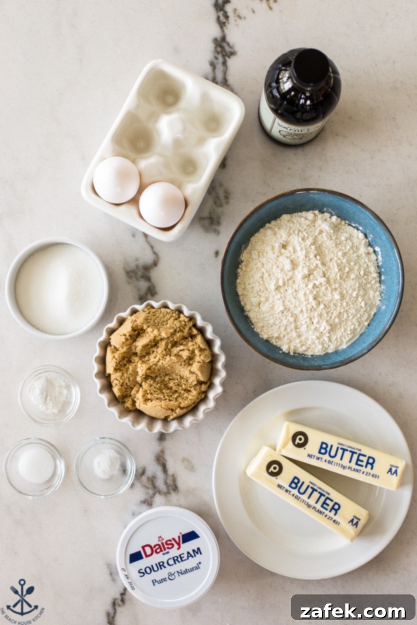 Overhead photo of all the meticulously laid out ingredients for making a brown sugar bundt cake with caramel glaze, including butter, sugars, eggs, flour, sour cream, and vanilla extract.