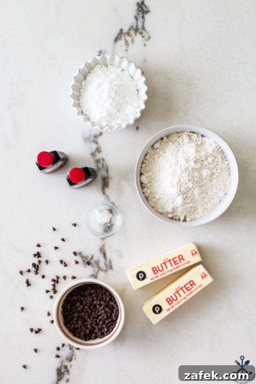 Tropical Chocolate Chip Cookie Logs 4 Overhead photo of bowls of key ingredients for coconut chocolate chip slice and bake cookies on a white marble background, including flour, confectioners' sugar, butter, and mini chocolate chips.