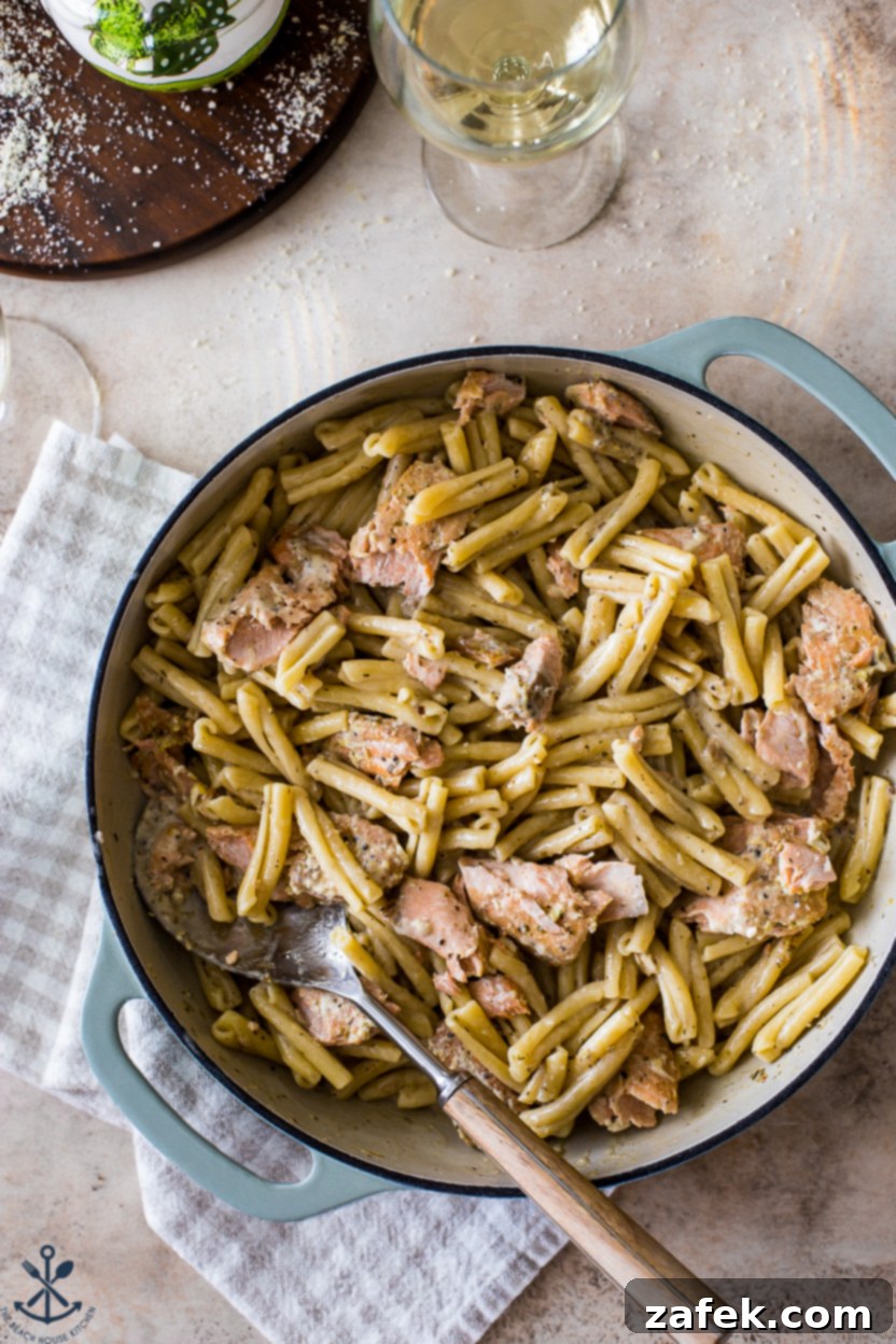Overhead photo of a large baking dish of pasta with salmon, garnished with fresh herbs and lemon wedges, showcasing a vibrant and appealing meal.