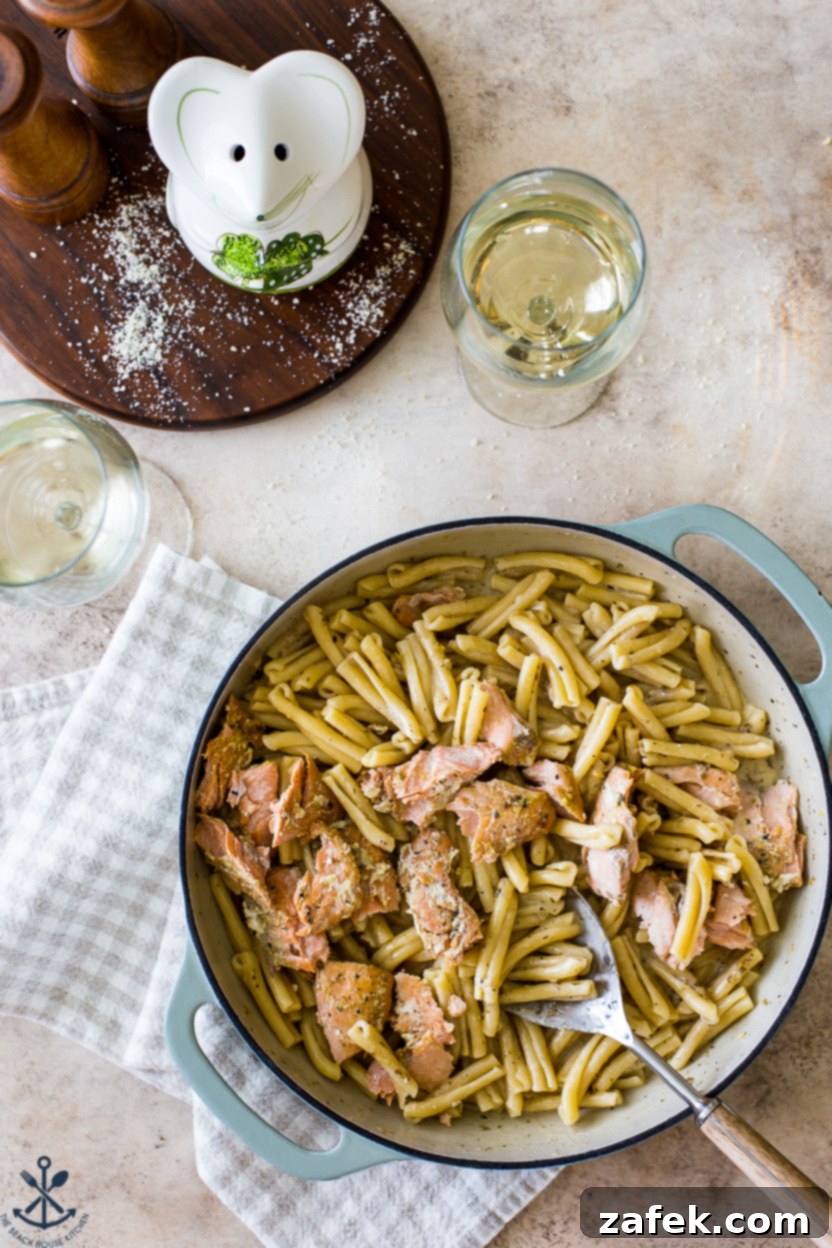 Overhead photo of a skillet filled with creamy lemon garlic pasta and succulent salmon flakes, ready to serve.