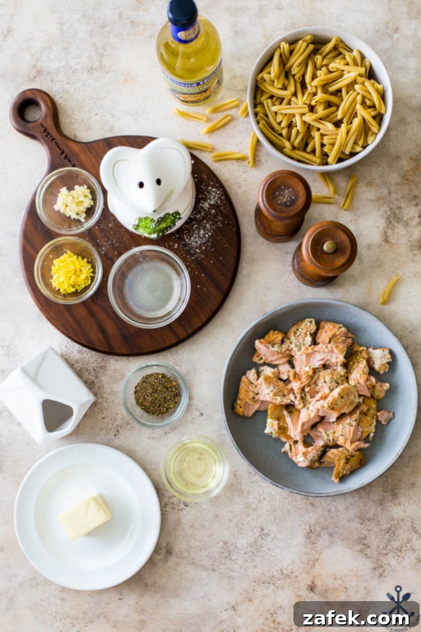 Overhead photo of fresh ingredients for pasta with salmon: salmon fillets, casarecce pasta, garlic, lemons, heavy cream, butter, and seasonings.