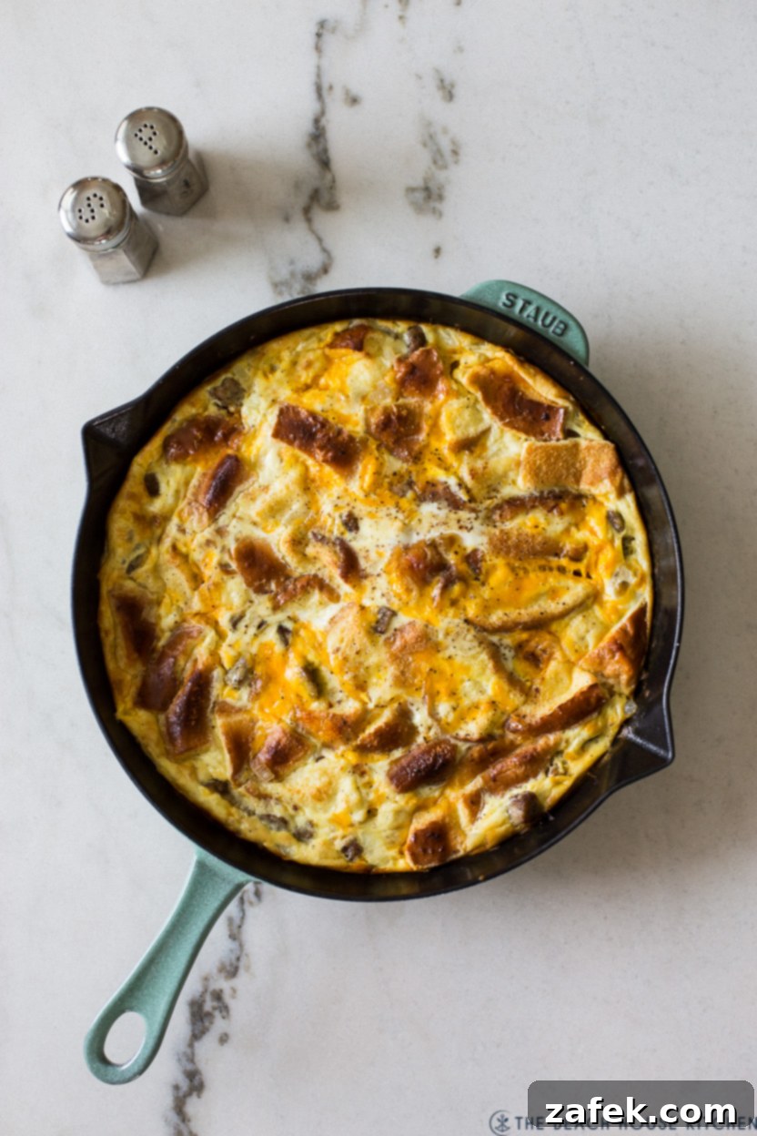 Decadent Skillet Brioche Sausage Egg Strata 4 Overhead shot of a breakfast strata, freshly baked in a skillet, showcasing its golden crust and bubbly cheese