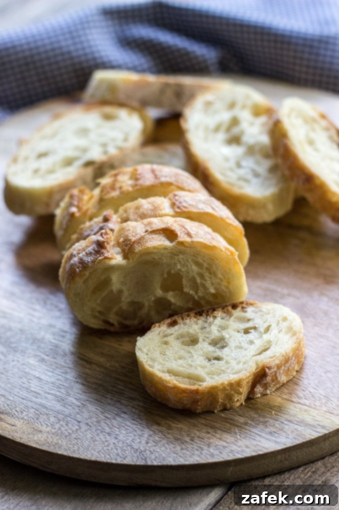 Overhead view of a single bowl of Caramelized Onion Soup garnished with fresh parsley, cheese, and baguette