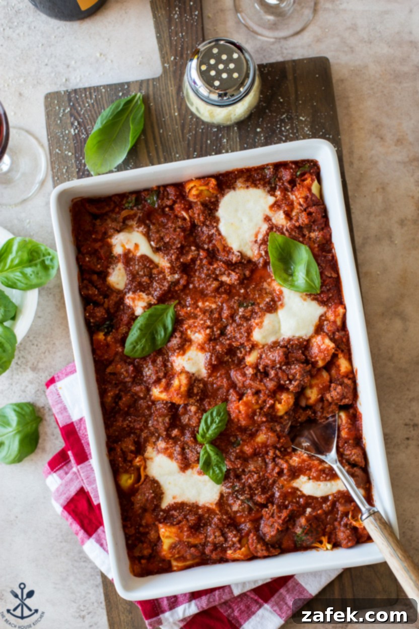 Cheesy Italian Sausage Tortellini Casserole 2 A top-down shot of a golden-brown Italian Sausage Tortellini Bake in a baking dish, garnished with fresh basil leaves.