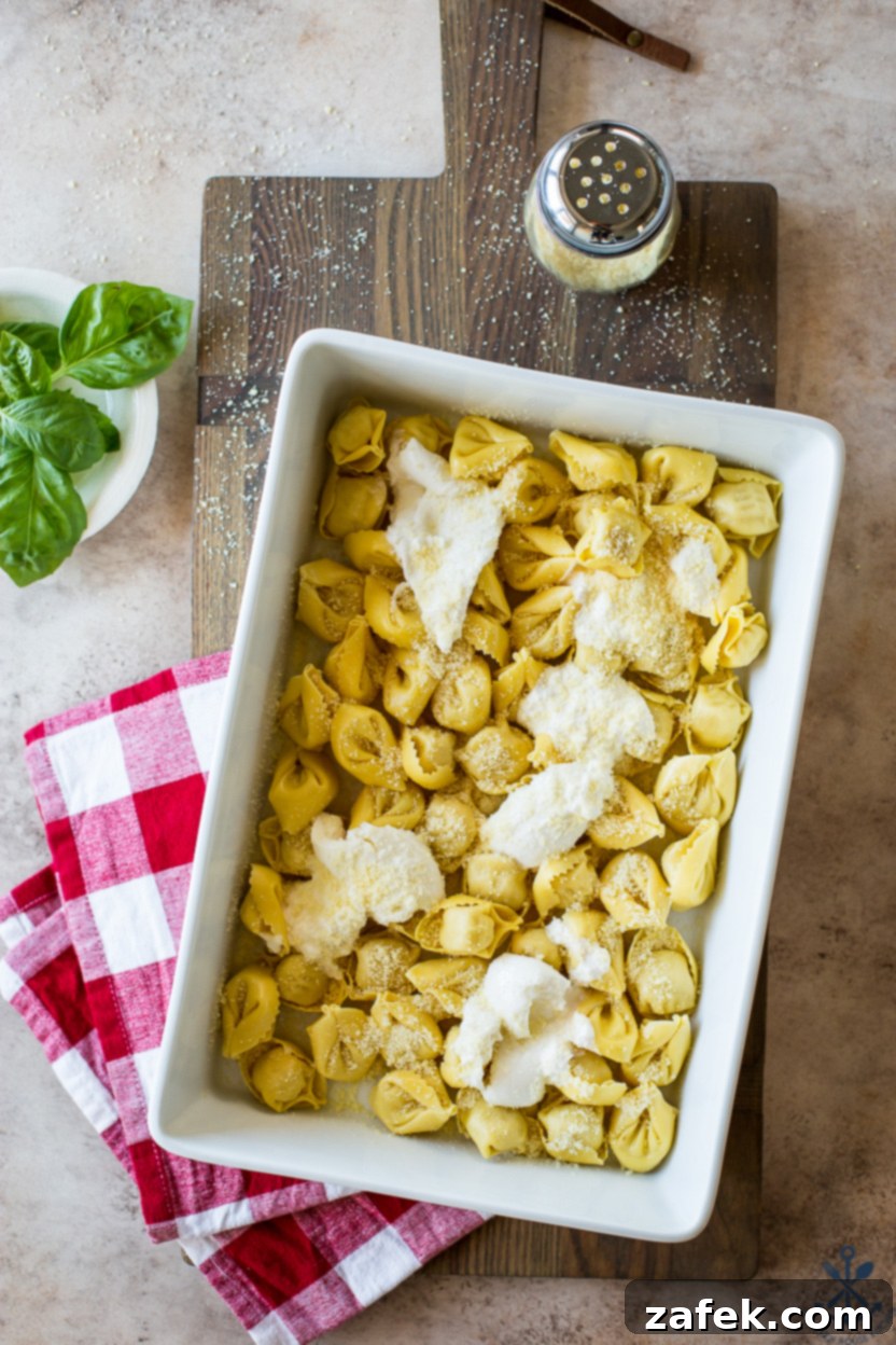 Cheesy Italian Sausage Tortellini Casserole 5 A baking dish filled with Italian Sausage Tortellini Bake, topped with burrata and Parmesan cheese, ready to go into the oven.
