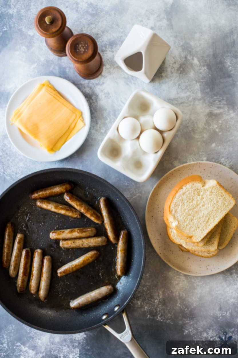 Overhead photo of a skillet of sausage links, a plate of cheese slices, eggs, bread, milk, and salt and pepper, representing the simple ingredients for these delicious French toast roll-ups