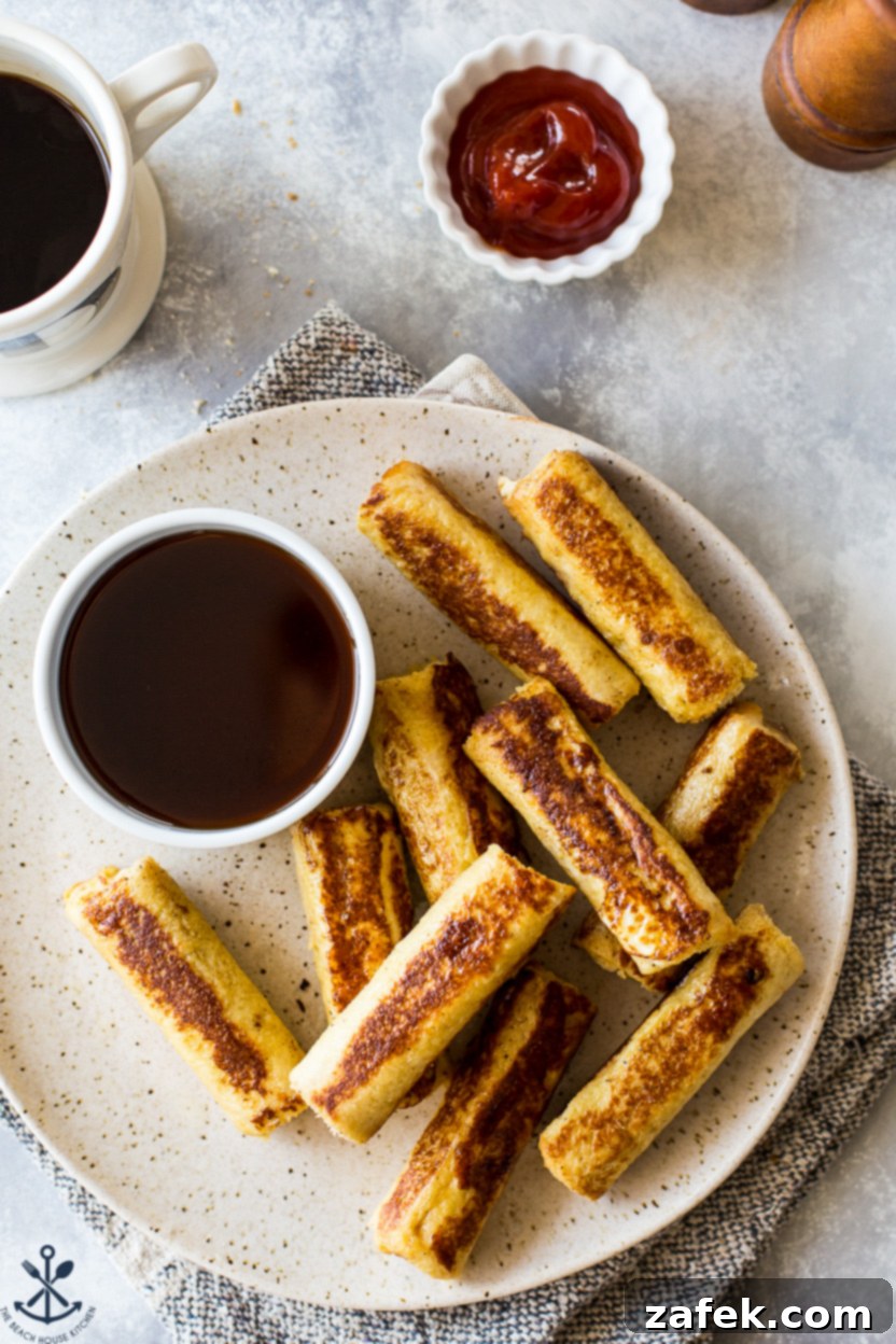 Up close overhead photo of golden brown French Toast Roll-Ups, showing the melted cheese and sausage peeking out, emphasizing their deliciousness
