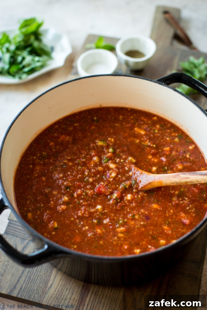 A large pot filled with a rich red gazpacho, ready to be chilled and served.