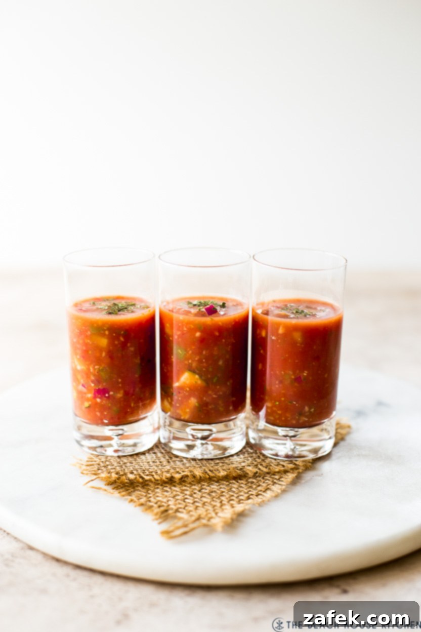 Three elegant shooter glasses filled with bright red gazpacho, perfect for a light appetizer.