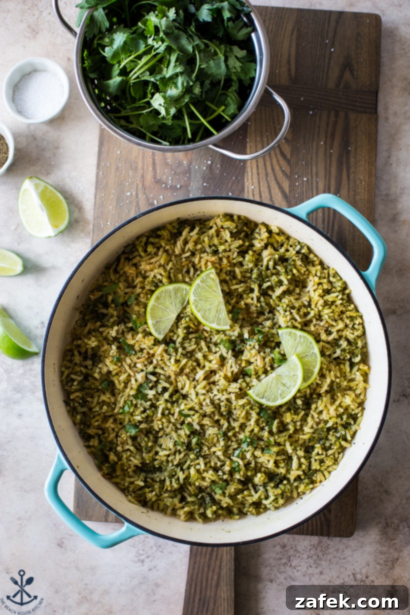 Overhead photo of a skillet filled with arroz verde (Mexican green rice), garnished with fresh herbs and lime wedges, ready to serve.