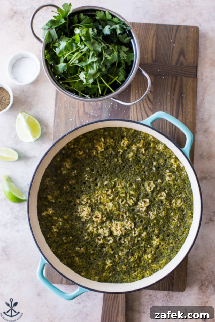 Overhead close-up photo of a skillet filled with vibrant green Mexican rice, garnished with fresh cilantro, ready to be served.