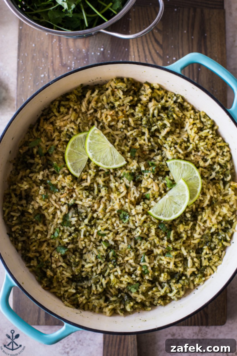Up close overhead photo of a skillet of perfectly cooked Arroz Verde (Mexican Green Rice), showing the fluffy grains and vibrant green color, garnished with cilantro.